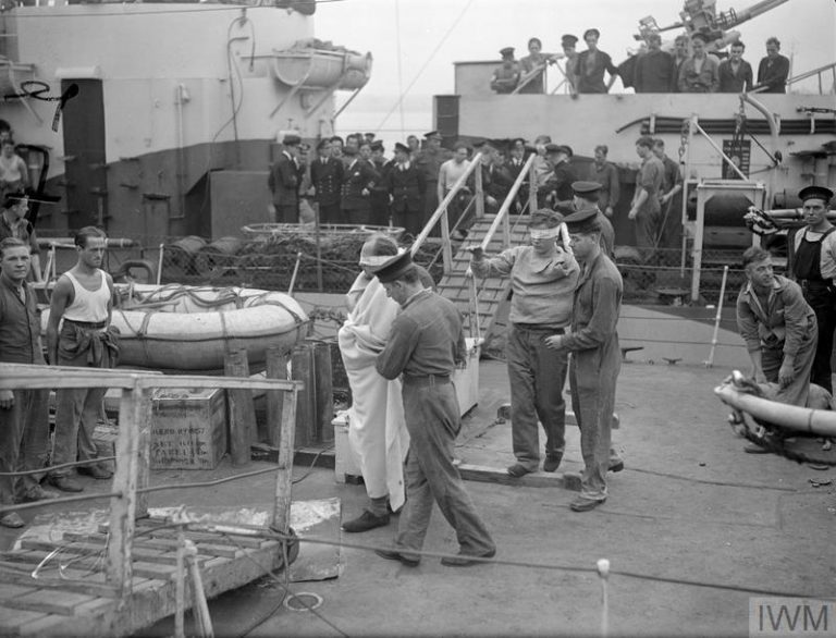 BRITISH NAVAL FORCE SINKS THREE E-BOATS. 19 SEPTEMBER 1944, HARWICH. THE FRIGATE HMS STAYNER RETURNED WITH PRISONERS PICKED UP DURING THE BRISK ENGAGEMENT WITH THREE E-BOATS NORTH OF DUNKIRK ON 18 SEPTEMBER 1944. THE STAYNER TOGETHER WITH CRAFT OF LIGHT COASTAL FORCES, ACCOUNTED FOR ALL THREE SHIPS. (A 25624) E-boat prisoners coming ashore from the STAYNER blindfolded. Copyright: © IWM. Original Source: http://www.iwm.org.uk/collections/item/object/205157325